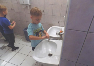 Tymek ćwiczy prawidłowe mycie rąk przy umywalce.